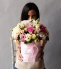 Flowers in a hatbox with roses and lisianthus in addition to peony varieties of roses